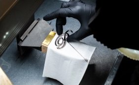 A gloved hand setting a brooch